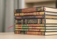 A stack of Islamic books including Quran and Hadith books