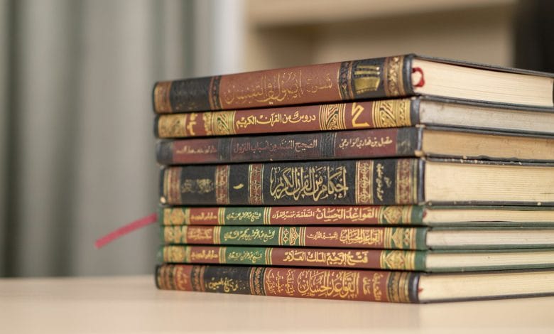 A stack of Islamic books including Quran and Hadith books